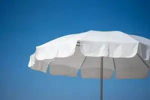 Terrasse ensoleillée avec parasol et plantes en pots créant des zones d'ombre