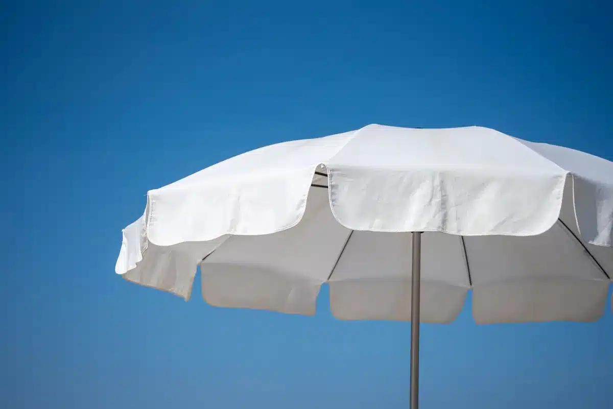 Terrasse ensoleillée avec parasol et plantes en pots créant des zones d'ombre