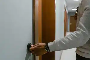Main d'une personne ajustant un thermostat mural dans un salon